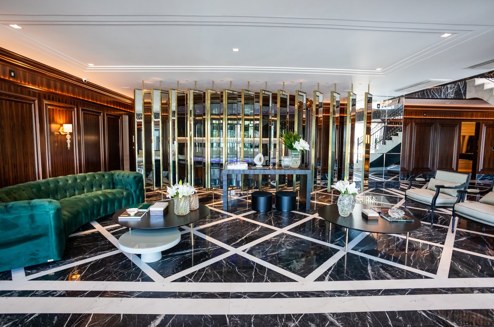 Hall de entrada do Cartier Residence, com piso de mármore geométrico e colunas espelhadas