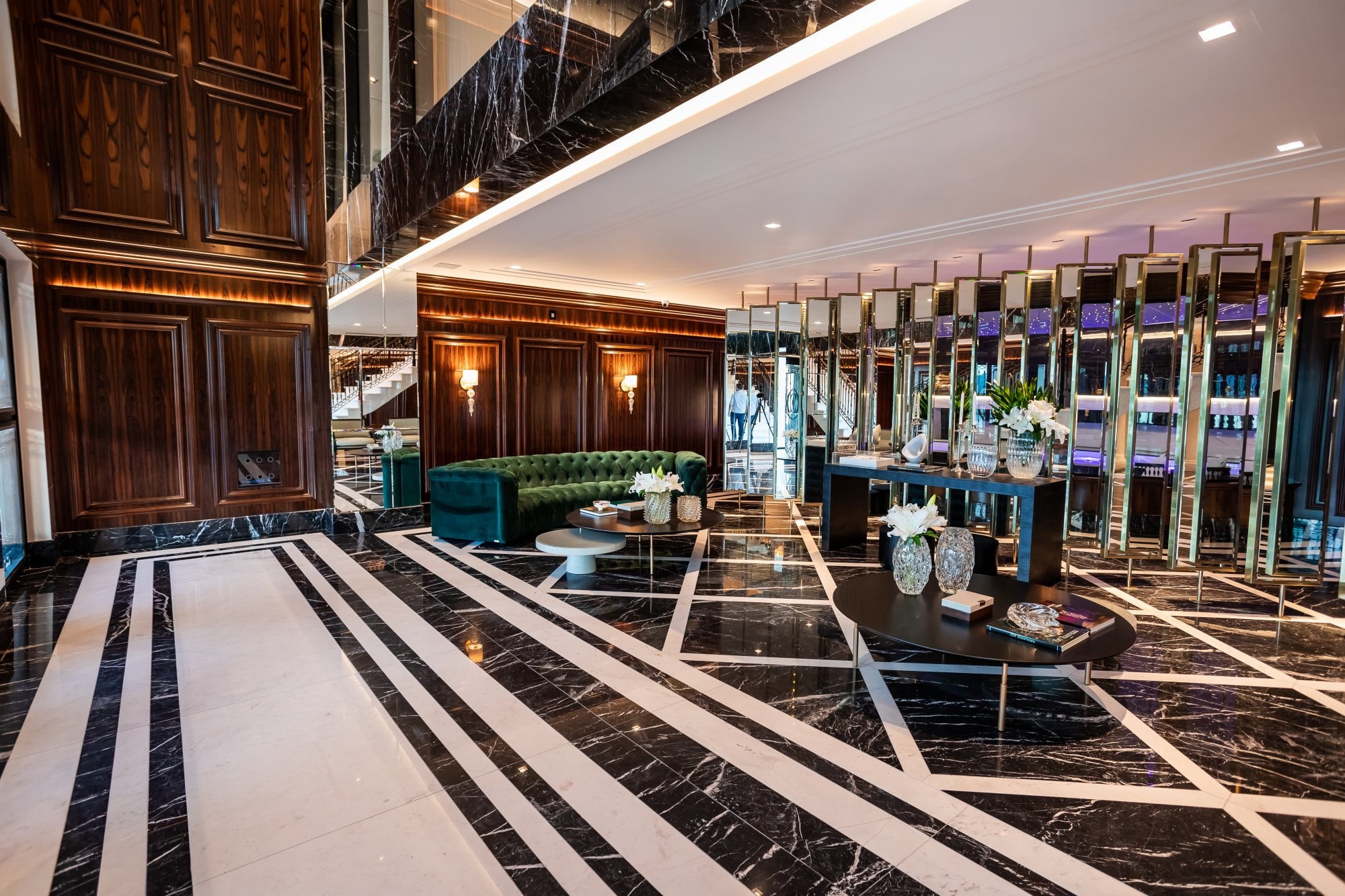Hall de entrada do Cartier Residence, outro ângulo, com sofá de veludo verde e escadaria ao fundo