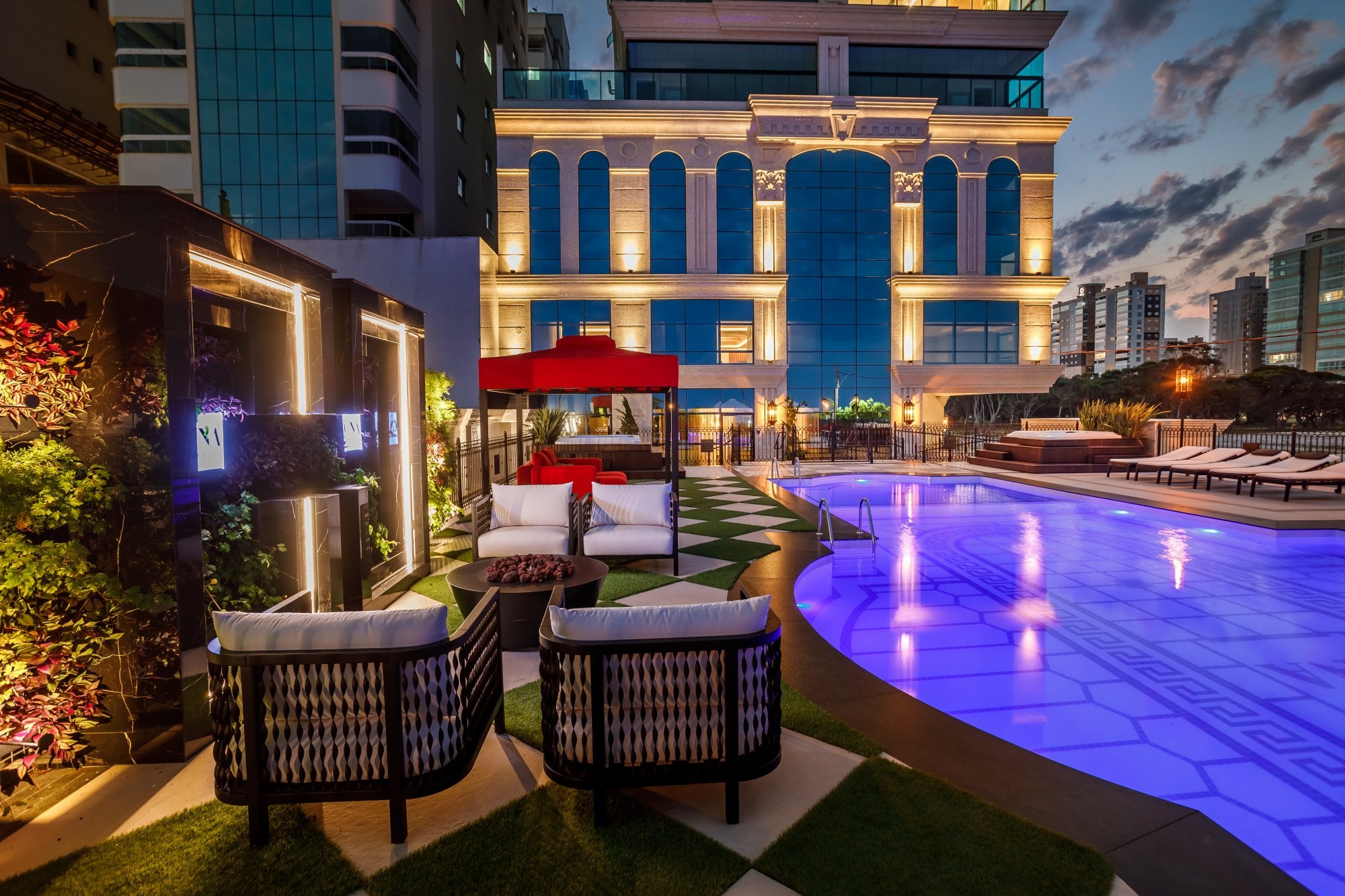Área da piscina do Cartier Residence ao anoitecer, com a fachada iluminada